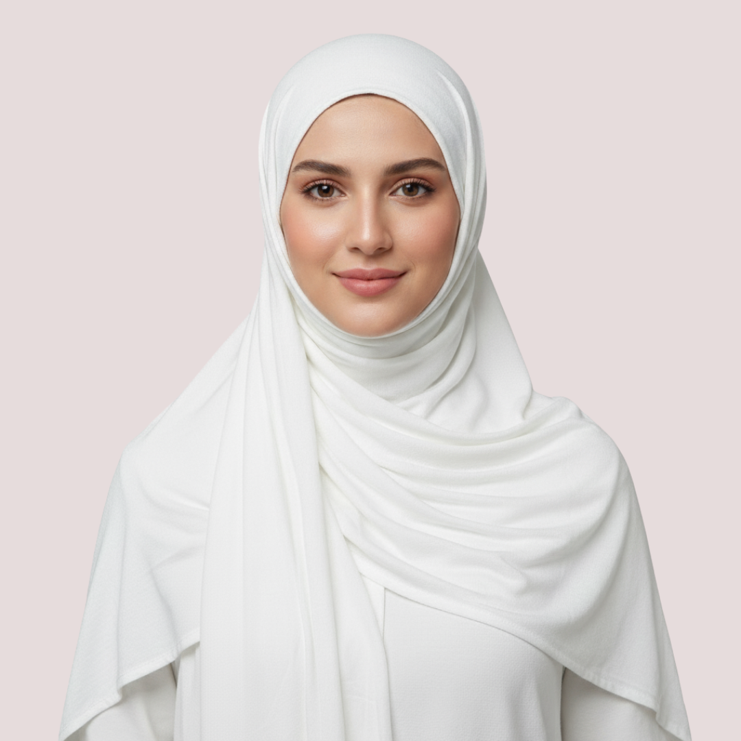 Woman wearing a white hijab against a light pink background