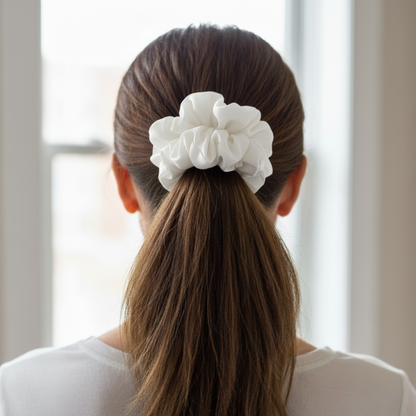 Person with a white scrunchie in their hair, standing in front of a window.