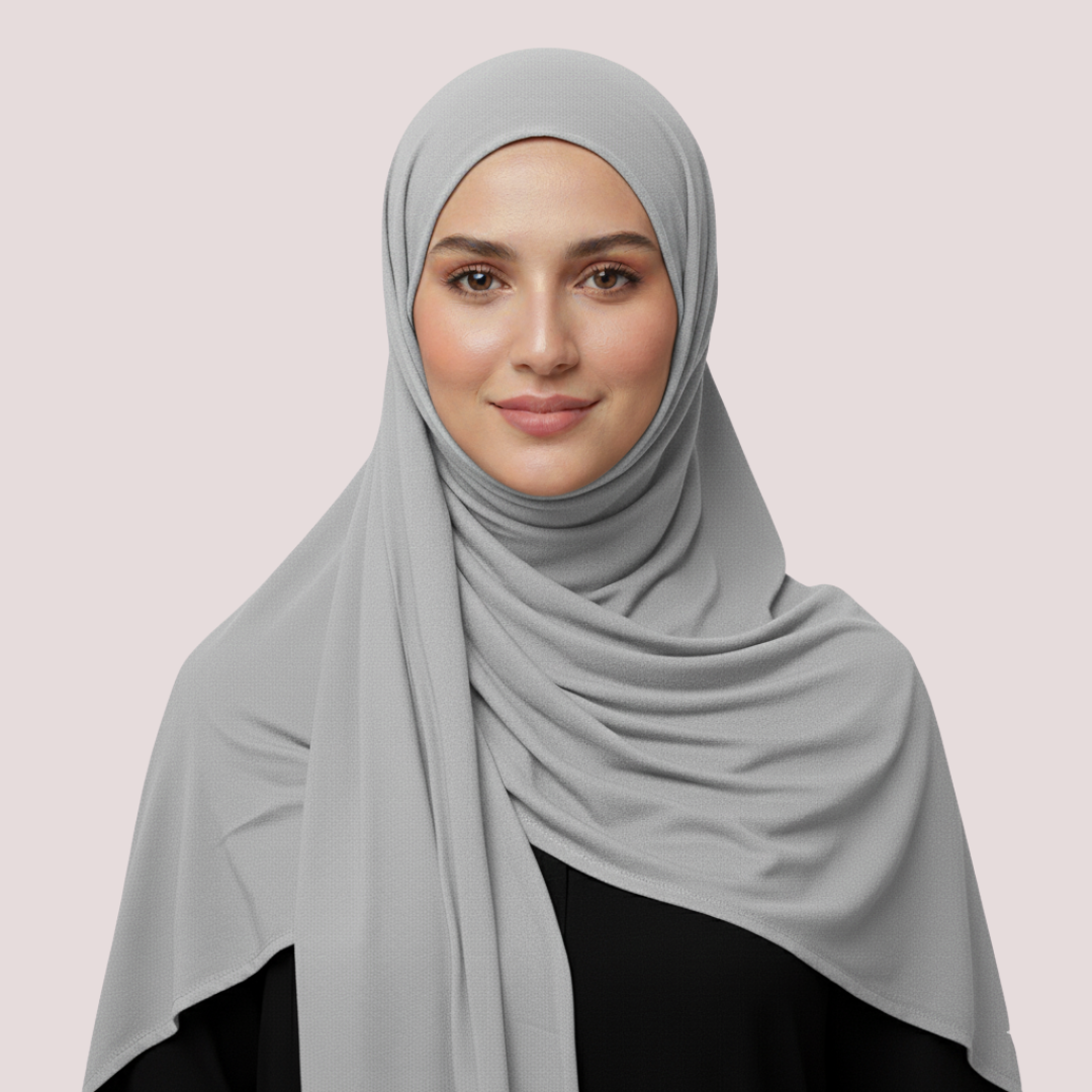 Woman wearing a light gray hijab on a plain background
