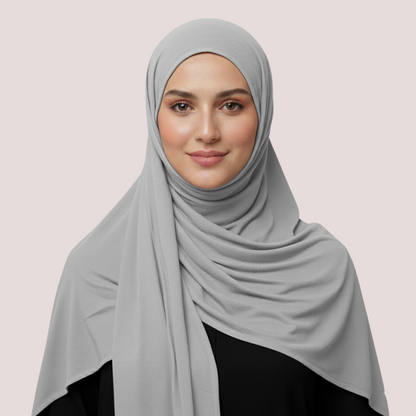 Woman wearing a light gray hijab on a plain background