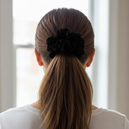 Person with a high ponytail wearing a black scrunchie, standing in front of a window.