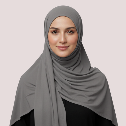 Woman wearing a gray hijab on a plain background