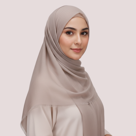 Woman wearing a beige hijab against a light background